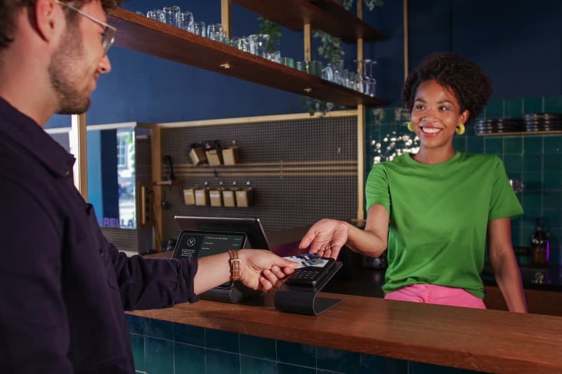 Eine Friseurin kassiert einen Kunden mit ihrem Shore Kassensystem ab.