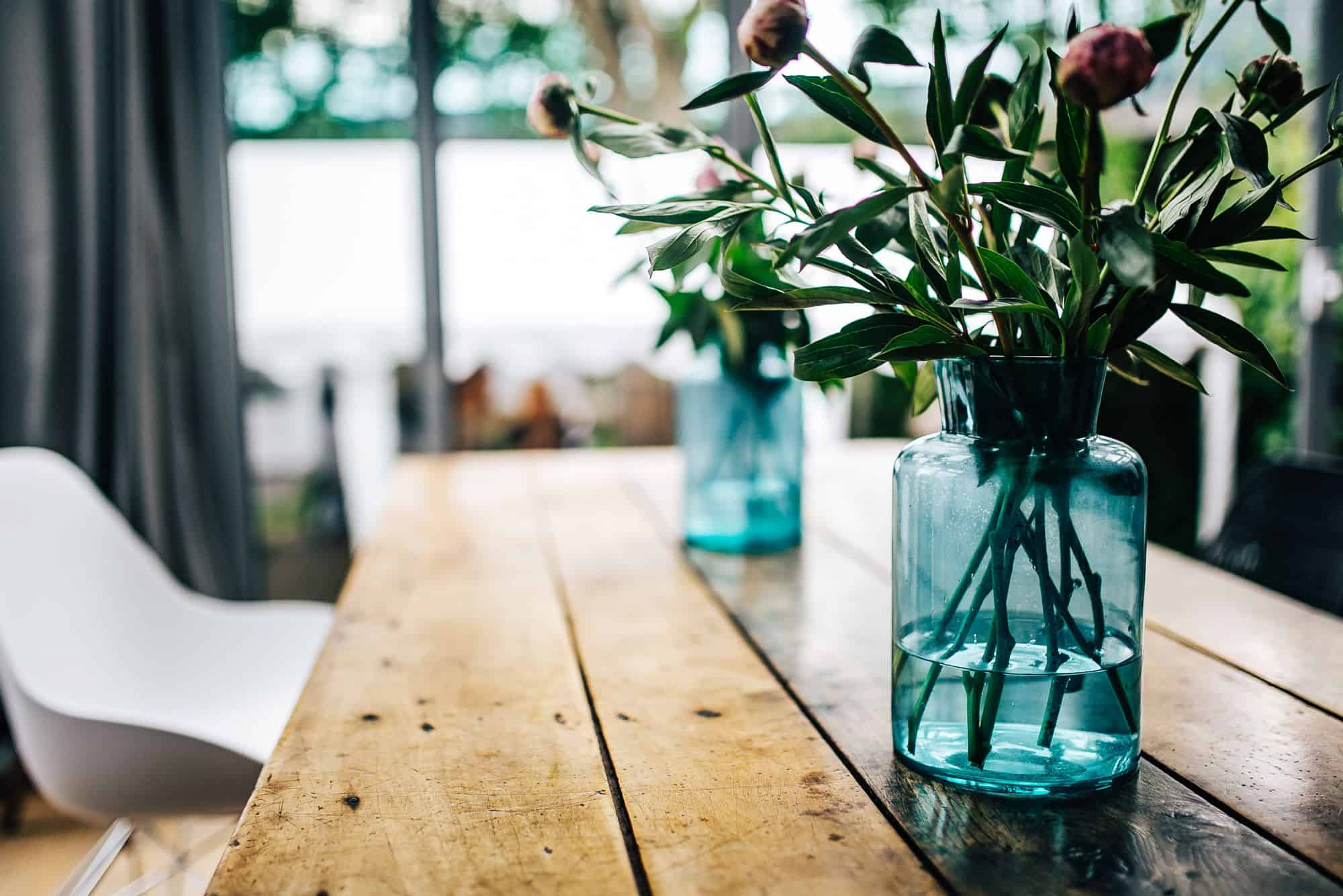 Auf einem Holztisch stehen zwei Vasen mit Blumen