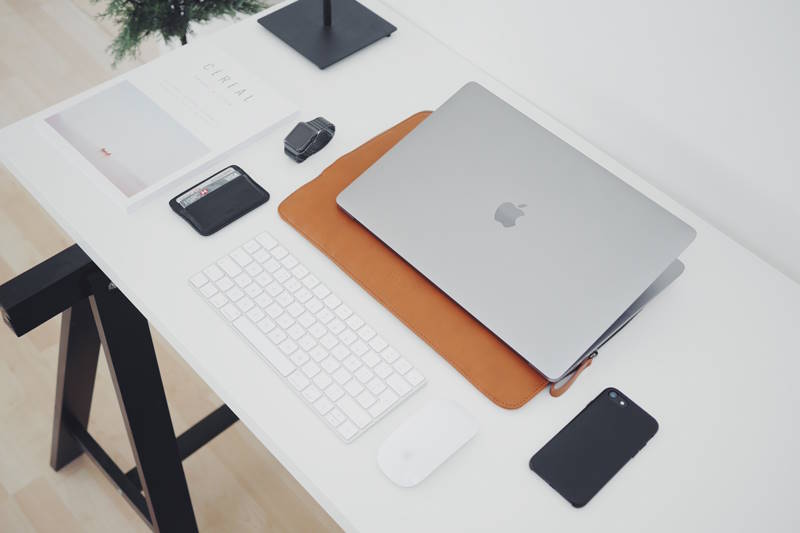 Schreibtisch mit Laptop, Tastatur und Handy