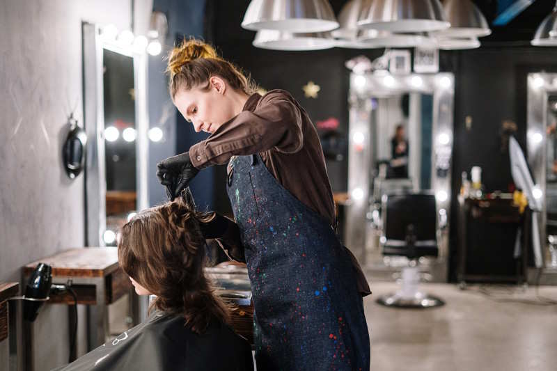 Eine Frau frisiert einer anderen Frau die Haare