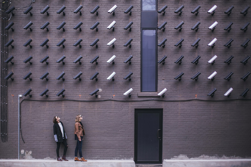 Überwachungskameras an einer Wand filmen zwei Menschen