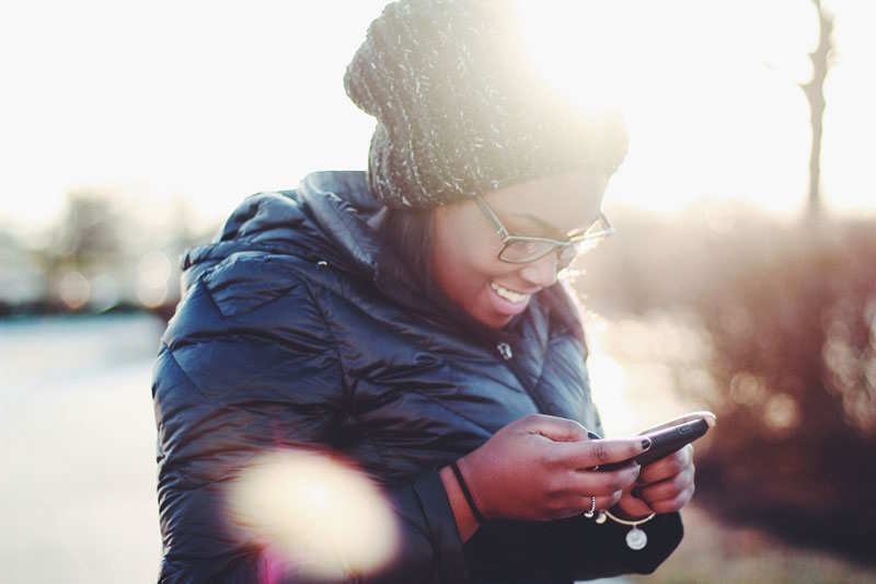 Frau liest lächelnd am Handy eine SMS