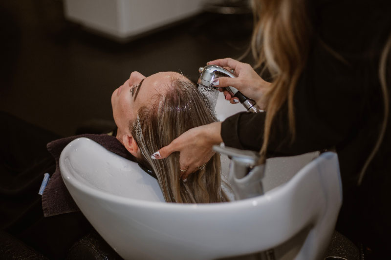 Frau bekommt ihre Haare von einer Friseurin gewaschen