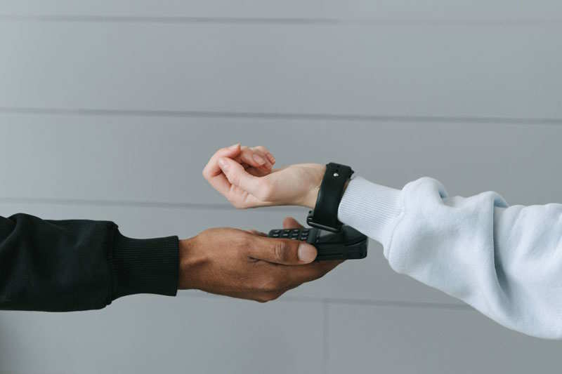 Zwei Hände, die Mobile Payment mit Smartwatch abwickeln