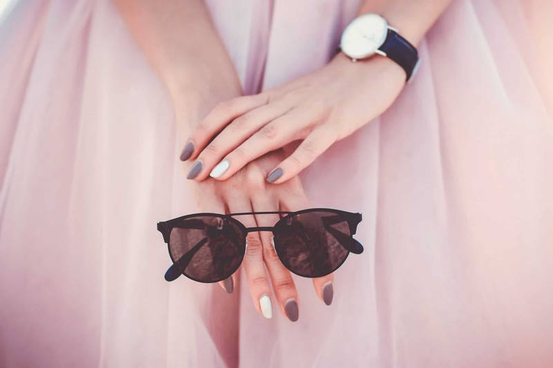 Eine Frau hält eine Sonnenbrille und hat perfekt gemachte Fingernägel