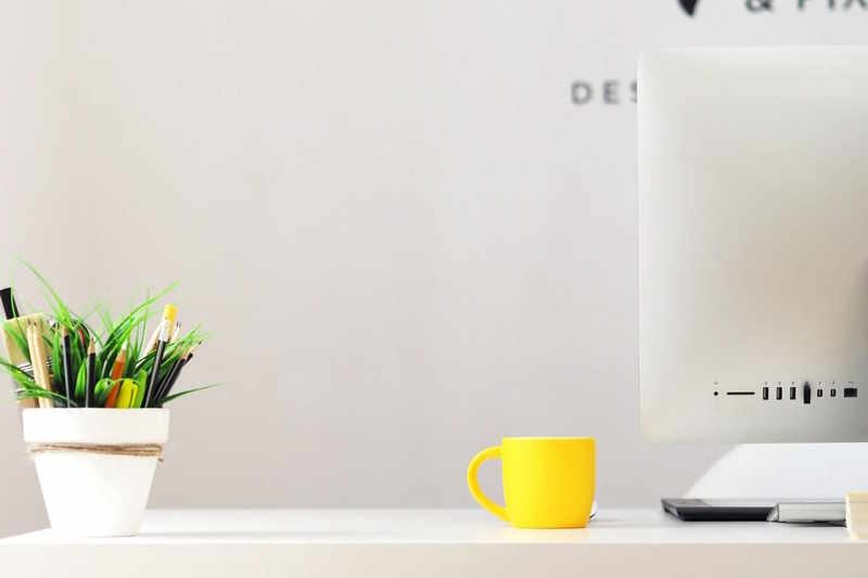 Tisch mit Pflanze, Tasse und Computer, der für Digitalisierung steht